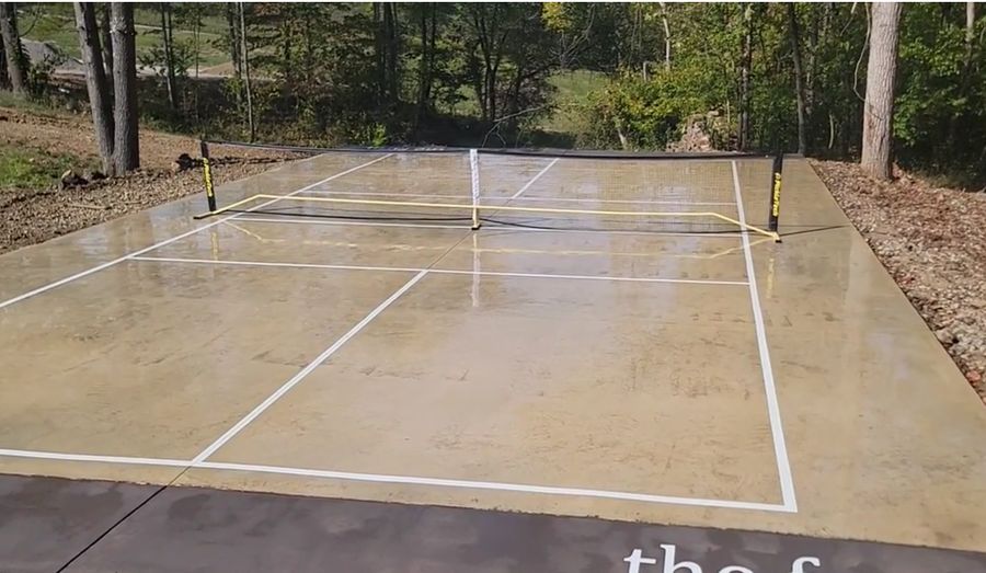 Regulation pickleball lines painted on a bare concrete slab with a portable net